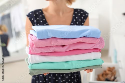 Woman with stack of clean clothes at home, closeup