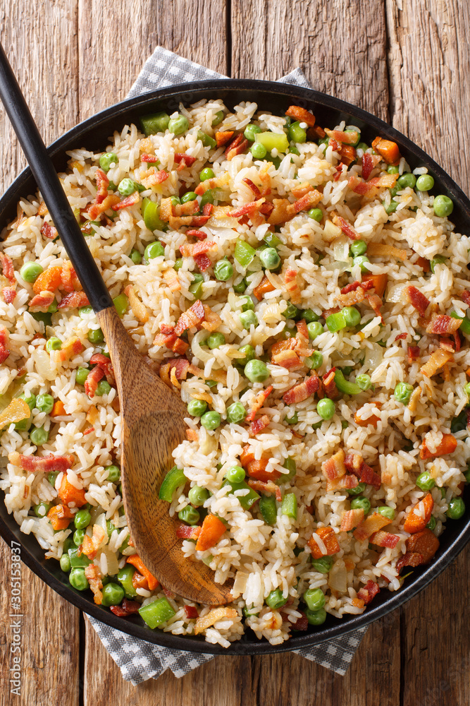 Fried rice with vegetables and bacon close-up in a plate. Vertical top view Fried rice with vegetables and bacon close-up in a plate. Vertical top view