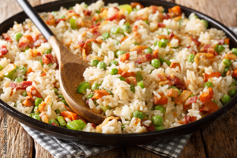 Tasty rice cooked with vegetables and bacon close-up in a plate. horizontal Tasty rice cooked with vegetables and bacon close-up in a plate. horizontal