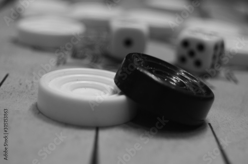 Board game backgammon. On the playing board are checkers and dice. Black and white.
