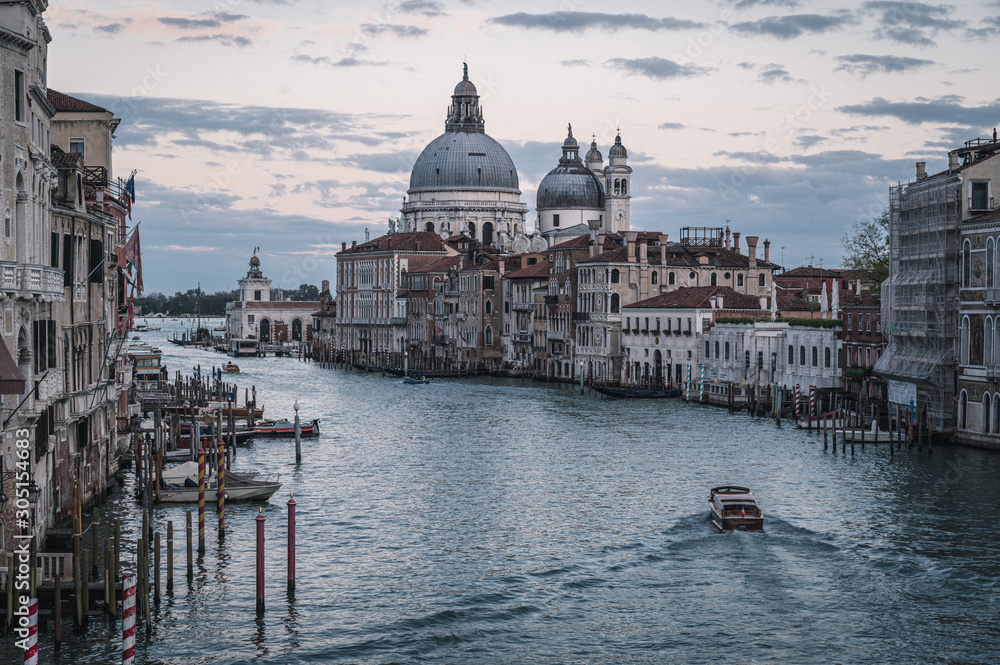 Venice Grand canal on sunset time. View of Basilica di Santa Maria della Salute, gondolas, water buses and typical Venetian houses and architecture. Beautiful and romantic Italian city.