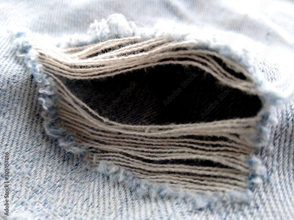 Ripped destroyed jeans background. Jeans torn denim texture. Blue jeans background.