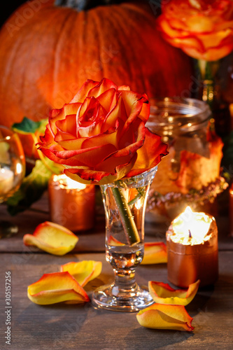 Autumn wedding decoration with pumpkins, orange roses and candles.