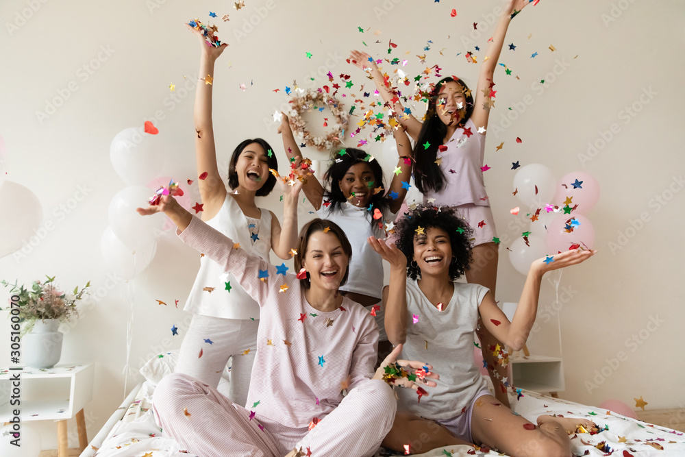 Smiling women group wear sleepwear celebrate party throw confetti up - obrazy, fototapety, plakaty 