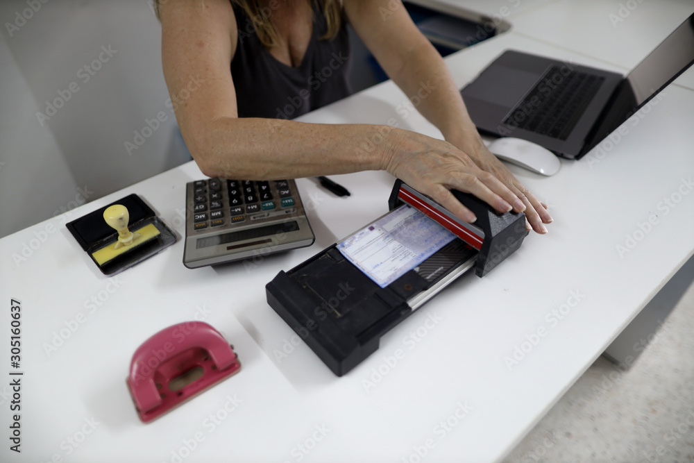 Female banker office worker holding and slowly swiping imprinting paper