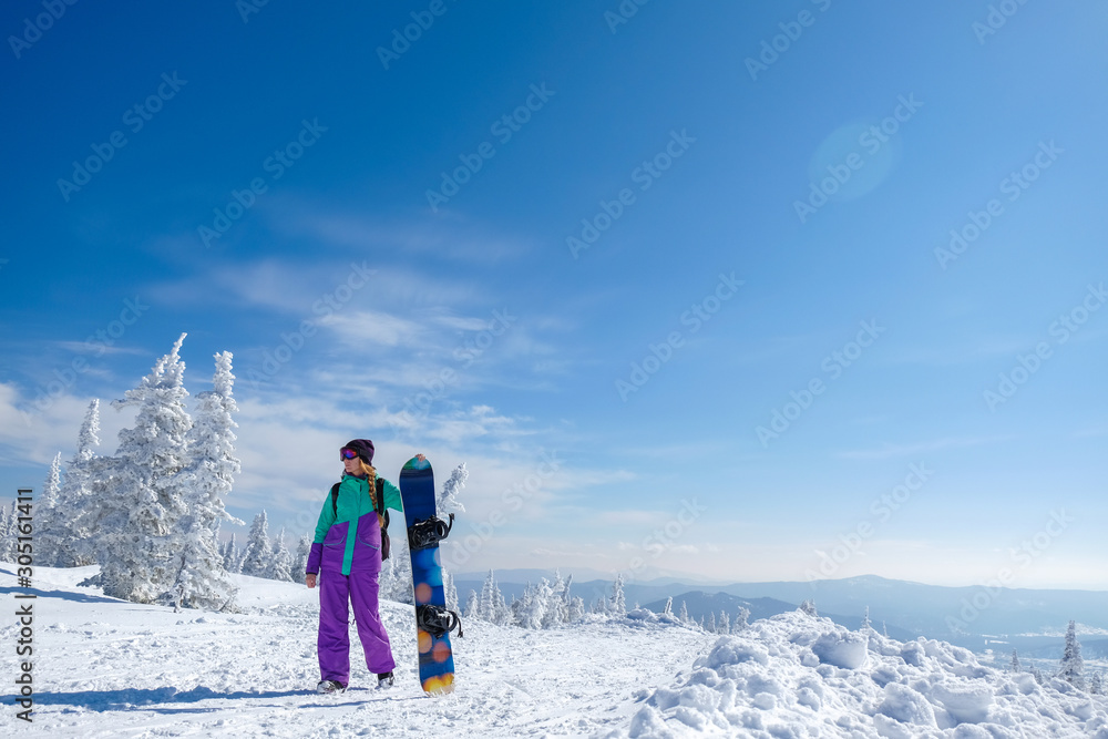 Young snowboarder in the mountains on top. Active rest on a snowboard.