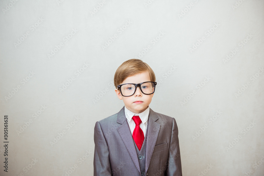 Portrait of young businessman of boy in a suit and spectacled on gray background Portrait of young businessman of boy in a suit and spectacled on gray background