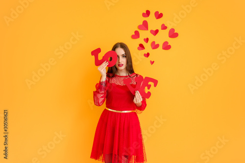 Beautiful young woman with word LOVE and hearts on color background. Valentine's Day celebration