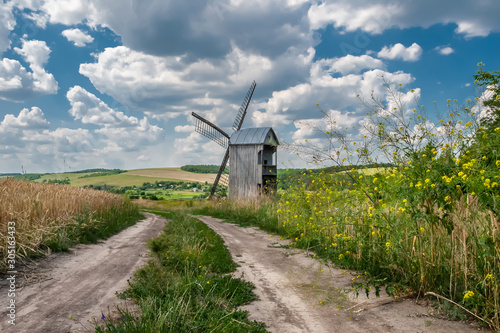 The road goes through a wheat field to a windmill.