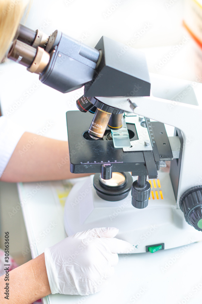 The lab technician looks into the microscope and records and analyzes the blood. The lab technician looks into the microscope and records and analyzes the blood.