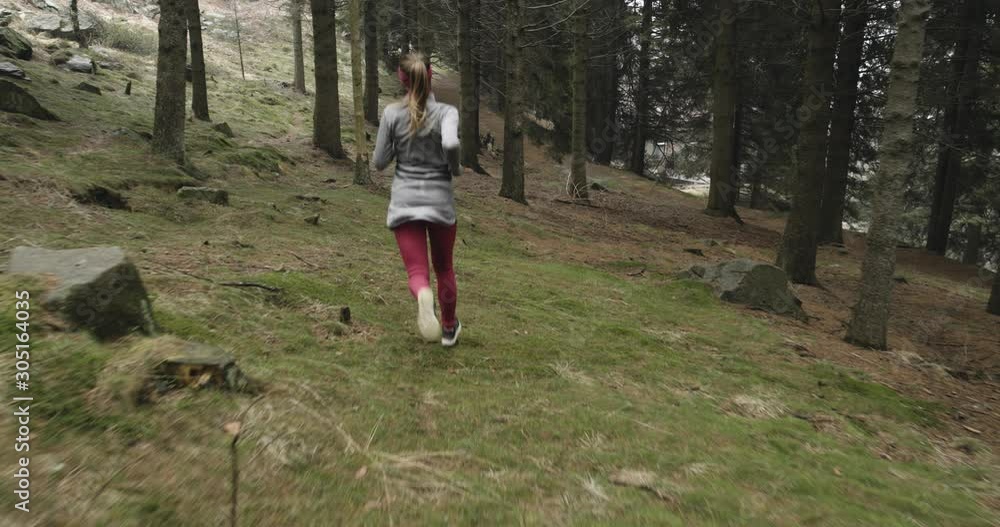 woman running active through forest in cold season. Bad weather running athlete in outdoor nature. Winter running in forest.Back view.sporty woman run. woman running active through forest in cold season. Bad weather running athlete in outdoor nature. Winter running in forest.Back view.sporty woman run.