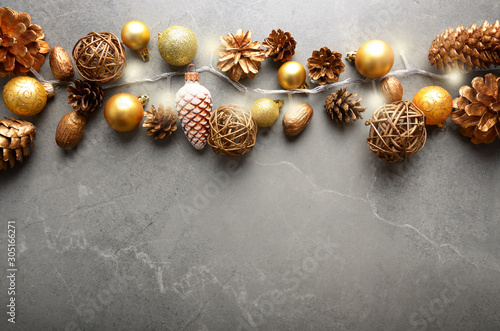 Flat lay view at Christmas decorations of gold and yellow cones glass balls and light garland on stone table. Space for text.