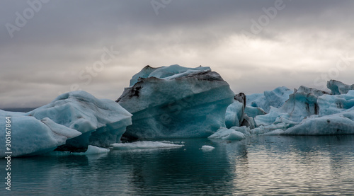 View of small icebergs in a lagoon against a cloudy sky