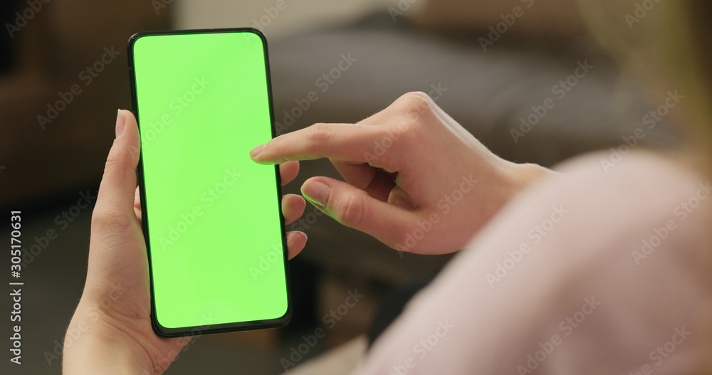 Young woman sitting on a couch and using smartphone with green screen Young woman sitting on a couch and using smartphone with green screen
