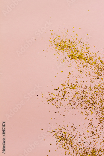 small gold sequins scattered on a pink background. background with beautiful shadow. poster. postcard view. space for your text. holiday. Christmas, women's day.