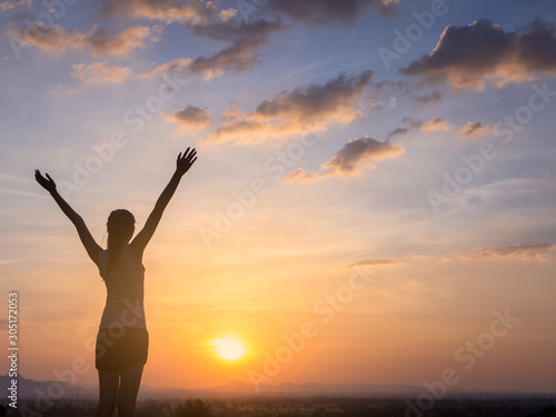 Free young woman raising arms to golden sunset. Freedom and success concept,relaxing and enjoying nature with copy space.