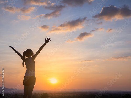 Free young woman raising arms to golden sunset. Freedom and success concept,relaxing and enjoying nature with copy space.