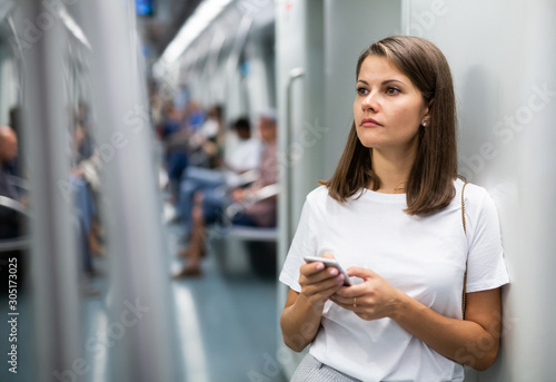 Woman using phone in subway car