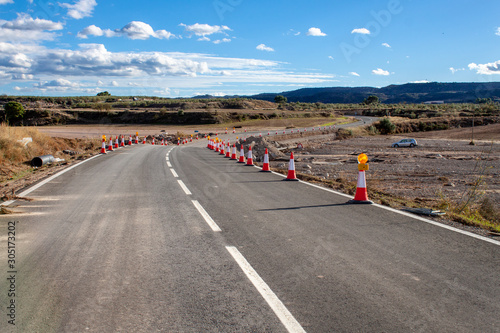 Road in disrepair due to a natural disaster marked with cones for precaution. Road under construction. Natural disaster.