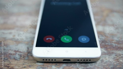 Incoming call on white mobile phone on wooden surface