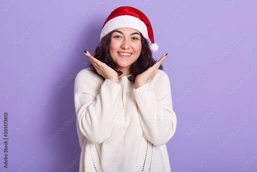 Image of beautiful tender joyful youngster having new year holidays, preparing for party, being in high spirits, feeling atmosphere of holiday, putting hands close to face, looking directly at camera. Image of beautiful tender joyful youngster having new year holidays, preparing for party, being in high spirits, feeling atmosphere of holiday, putting hands close to face, looking directly at camera.