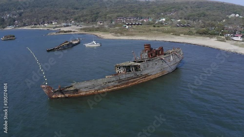 Ships graveyard. Two derelict partially submerged shipwreck, aground near the shore. Aerial descent shot. photo