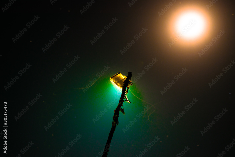 a blue digital light and it's reflection in the darkness and full moon in the background