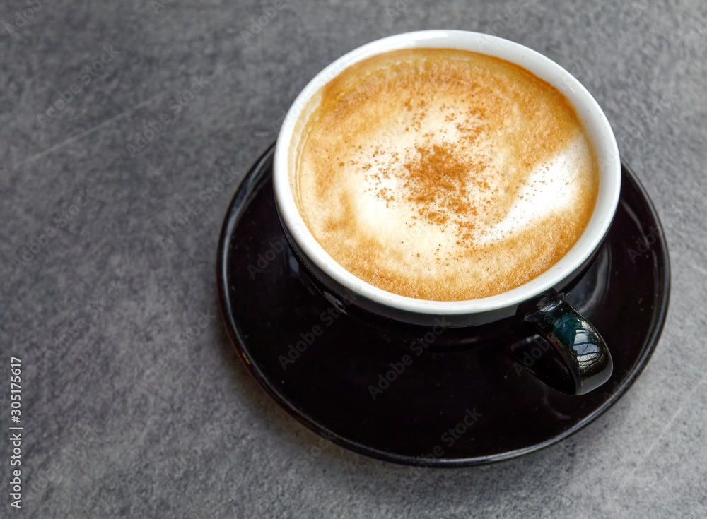 hot Italian cappuccino black cup on grey table background hot Italian cappuccino black cup on grey table background