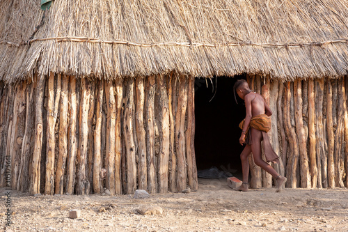 A kid walks into a hut in a Himba tribal village in Namibia, Africa