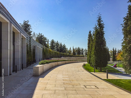 park footpath lined with stone tiles. Lawn and other vegetation