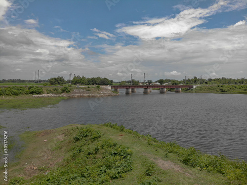 partially cloudy day , flowing river water with the rail bridge which adds to the beauty of the picture.