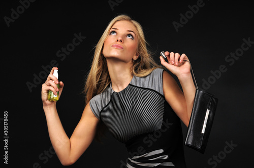 Young blond beautiful woman in dress perfuming herself with bodymist photo