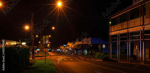 A magic night  with bright night lights and starry sky after midnight on empty Main Street in the town of Atherton. The Atherton Tableland, Far North Queensland, Australia. Street Photography.
