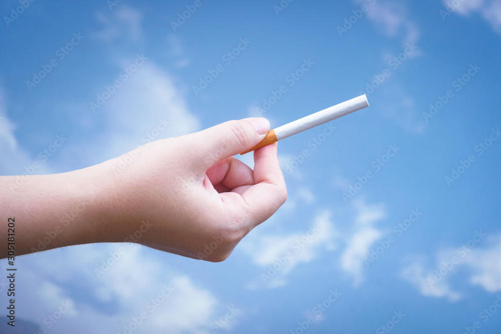 Hand is holding a cigarette on blue background,No smoking. Quitting from addiction concept. Hand is holding a cigarette on blue background,No smoking. Quitting from addiction concept.