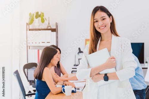Asian beautiful empower woman holding laptop and friend working at meeting room in office.Owner businesswoman startup with confident and cheerful.