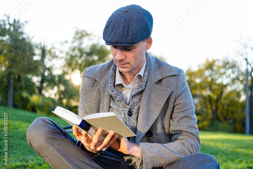 Young male hipster with retro bicycle read book in autumn park
