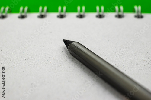 close up of black pencil on gray organizer sheet on green background.