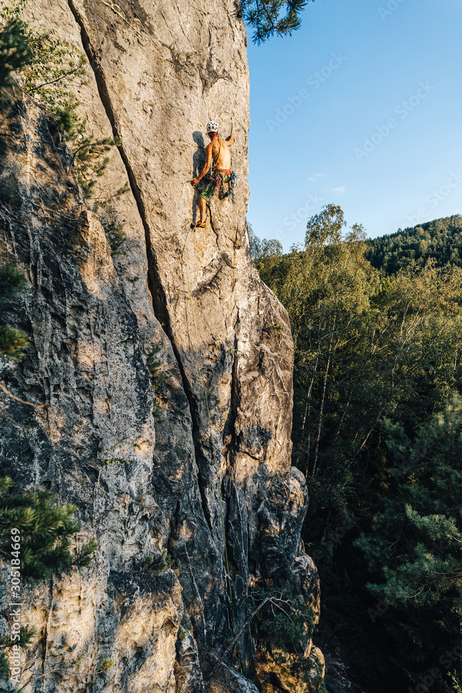 Climber climbing on a rock face. An alpinist ascending big rock clif. Sport and rock climbing, extreme outdoor sport. Sandstone traditional climbing. Climber climbing on a rock face. An alpinist ascending big rock clif. Sport and rock climbing, extreme outdoor sport. Sandstone traditional climbing.