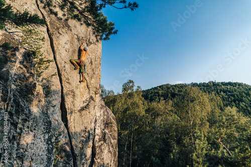 Climber climbing on a rock face. An alpinist ascending big rock clif. Sport and rock climbing, extreme outdoor sport. Sandstone traditional climbing.