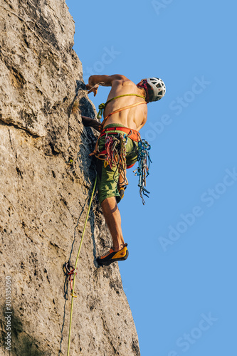 Climber climbing on a rock face. An alpinist ascending big rock clif. Sport and rock climbing, extreme outdoor sport. Sandstone traditional climbing.