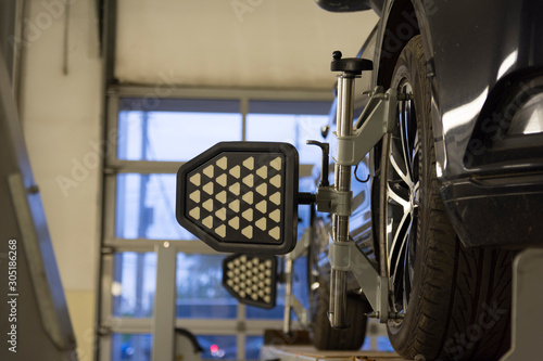 Car on stand with sensors on wheels for wheels alignment camber check in workshop of Service station