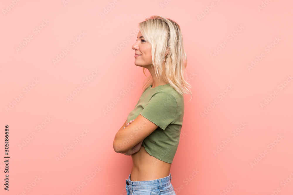 Young blonde woman over isolated pink background in lateral position Young blonde woman over isolated pink background in lateral position