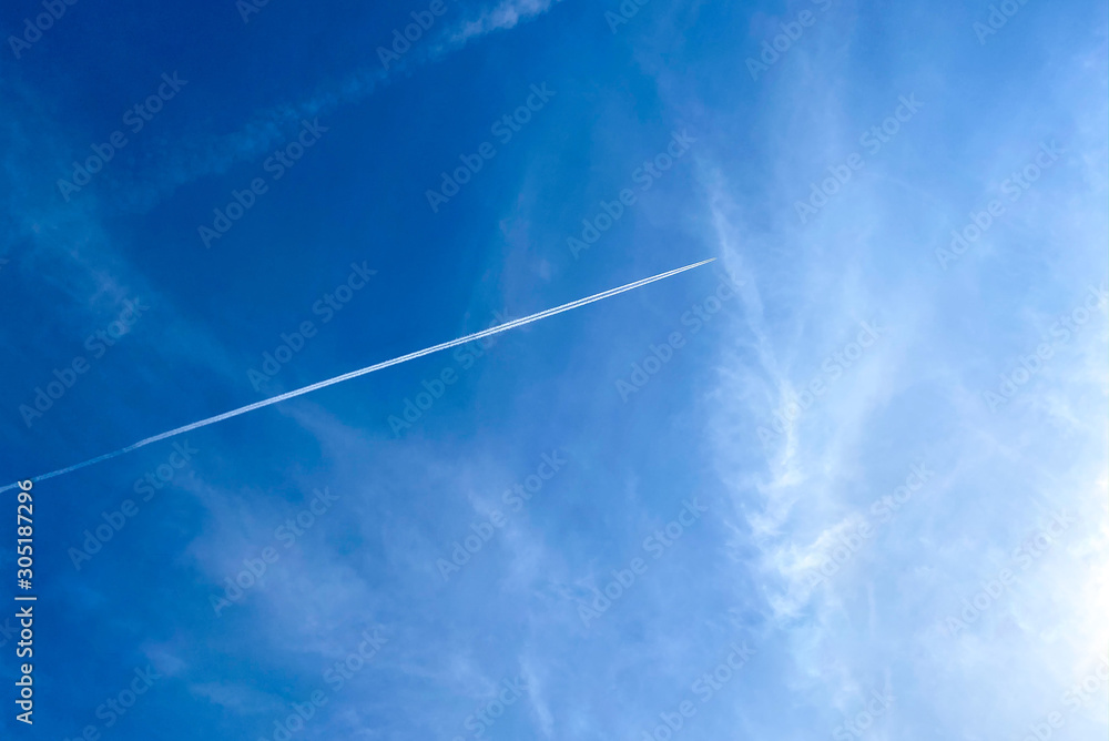 Trail of white smoke from the airplane on the blue sky and could. An airplane jets through a clear blue sky at speed leaving a trail behind. Trail of white smoke from the airplane on the blue sky and could. An airplane jets through a clear blue sky at speed leaving a trail behind.