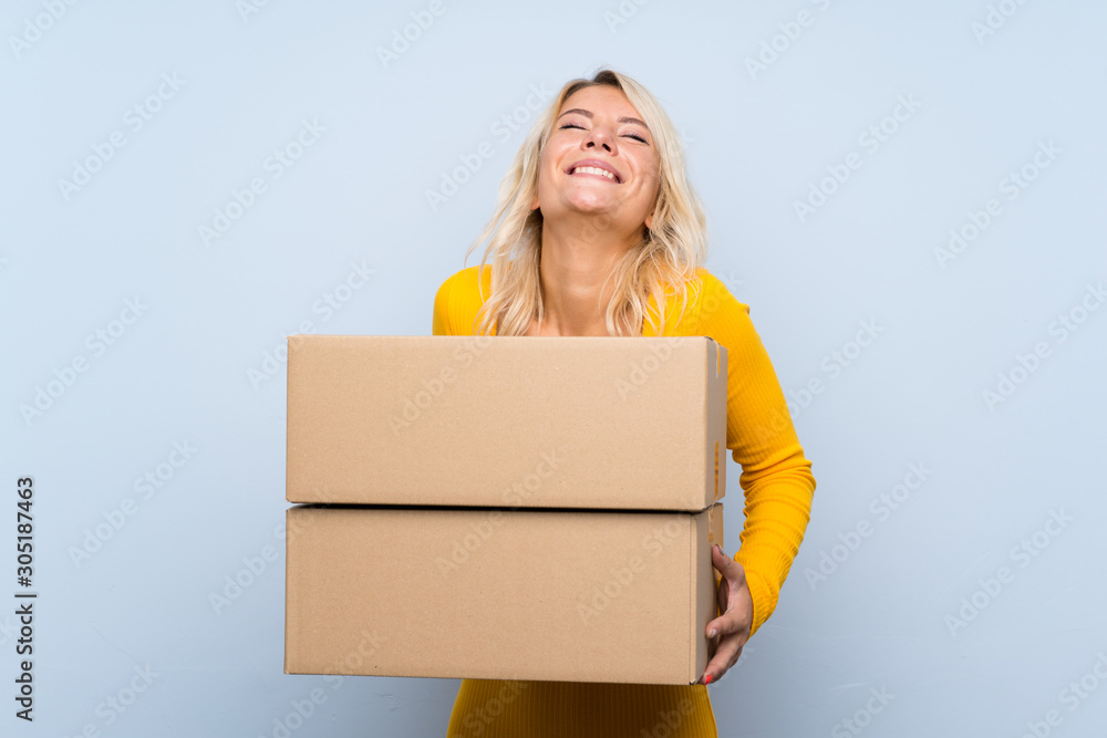 Young blonde woman over isolated background holding a box to move it to another site Young blonde woman over isolated background holding a box to move it to another site