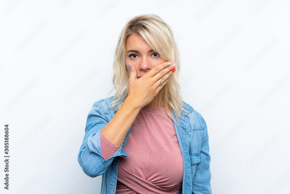 Young blonde woman over isolated white background covering mouth with hands Young blonde woman over isolated white background covering mouth with hands