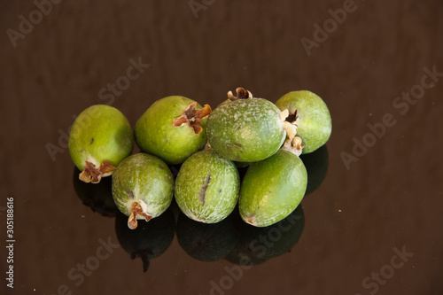 Fresh fruits of feijoa on a glass table with a reflection