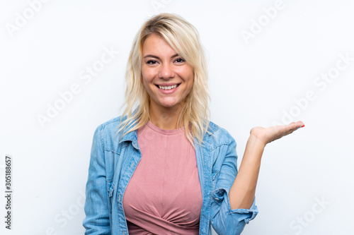 Young blonde woman over isolated white background holding copyspace imaginary on the palm to insert an ad