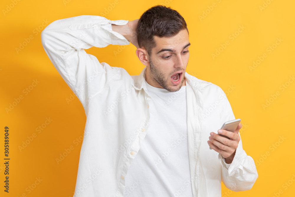 young man with surprise expression looking at mobile phone young man with surprise expression looking at mobile phone