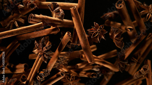 Fotografia Cinnamon barks with star anise lfying in the air