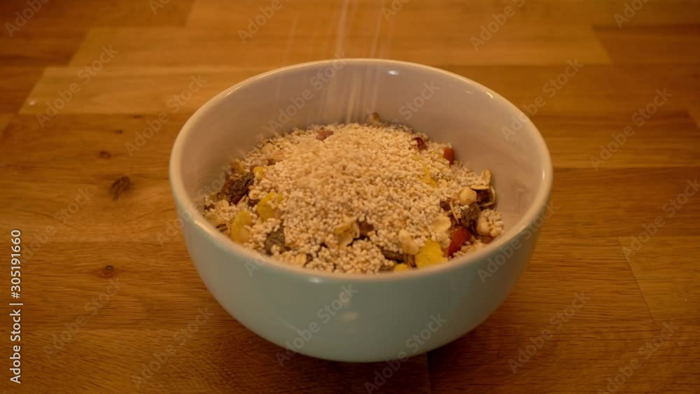 Amaranth falling into a breakfast bowl - preparing a vegan breakfast with oats, fruit, omega-3, amaranth, raisins almonds and oat milk Amaranth falling into a breakfast bowl - preparing a vegan breakfast with oats, fruit, omega-3, amaranth, raisins almonds and oat milk